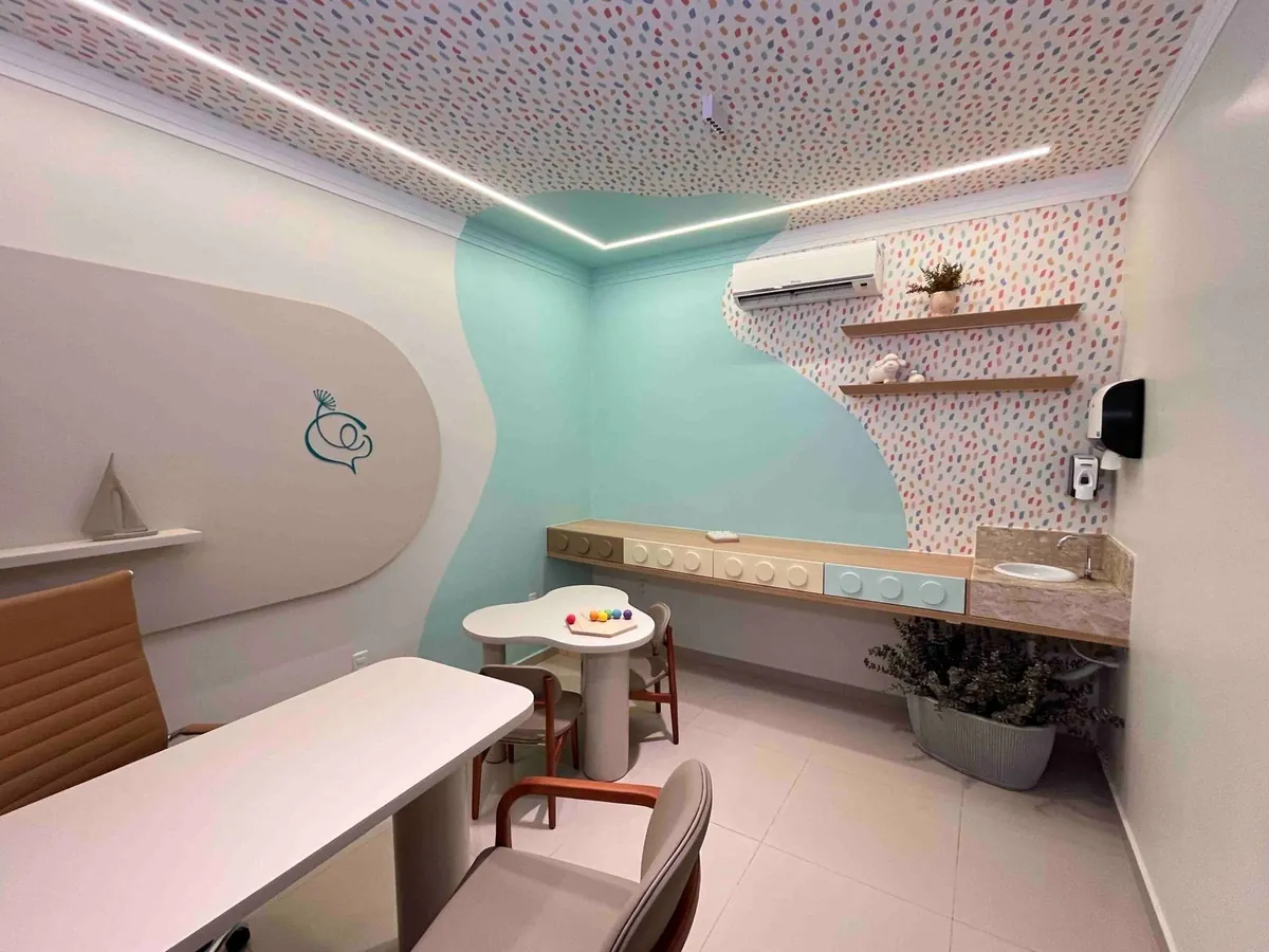 Consultório infantil com mesa pequena, cadeirinhas e brinquedos