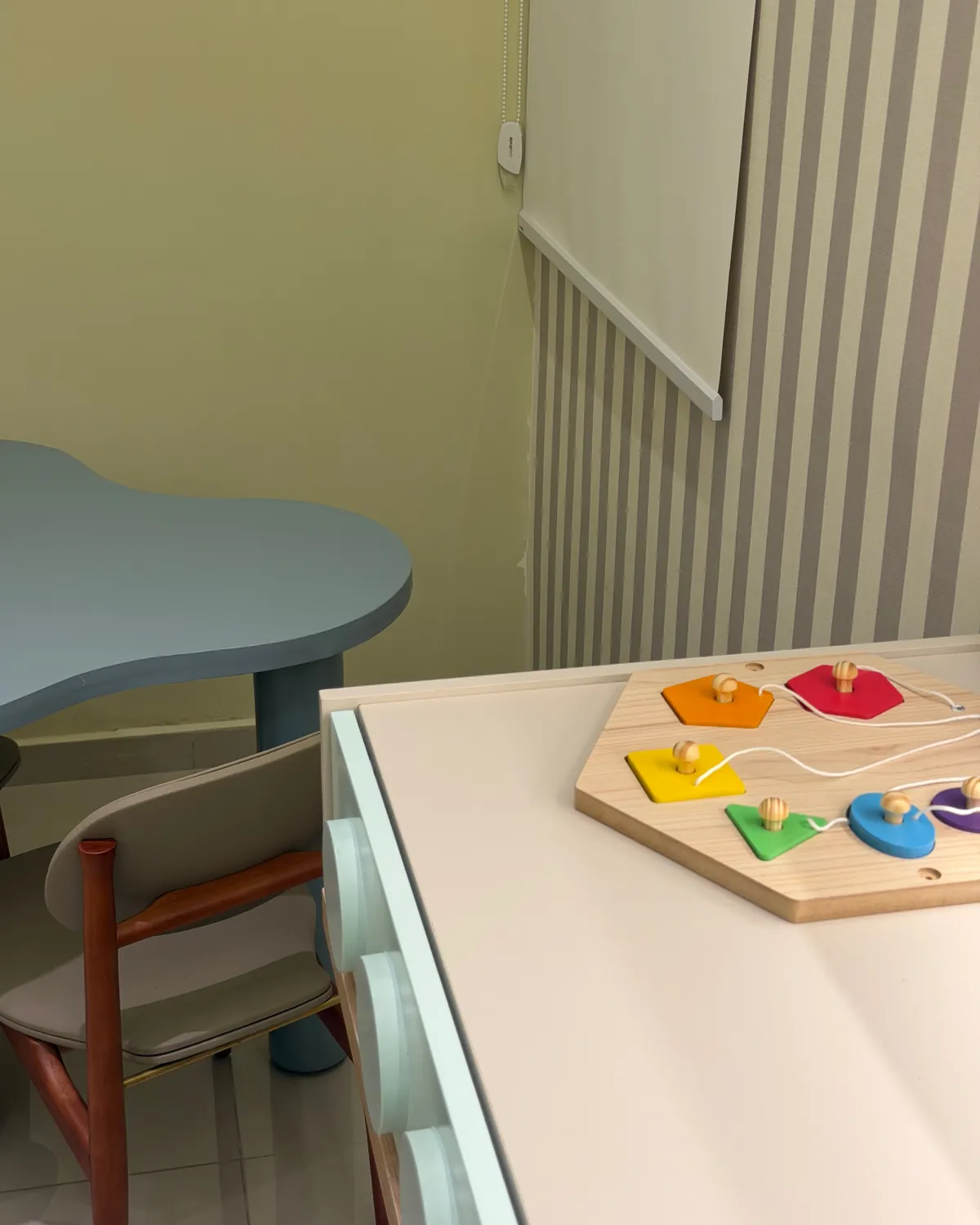 Brinquedo de encaixe com formas coloridas sobre a bancada, com mesinha e cadeira ao lado
