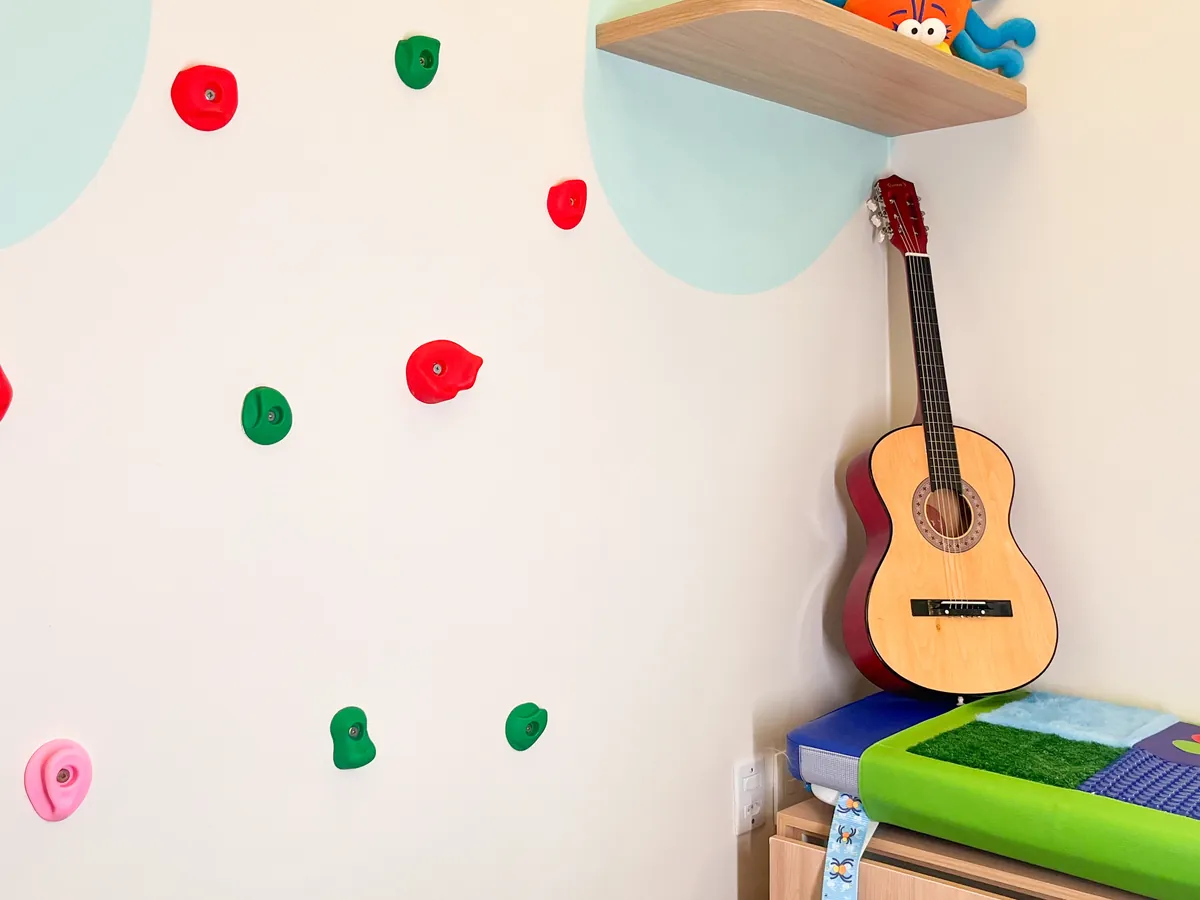 Violão de madeira encostado na parede colorida da sala sensorial