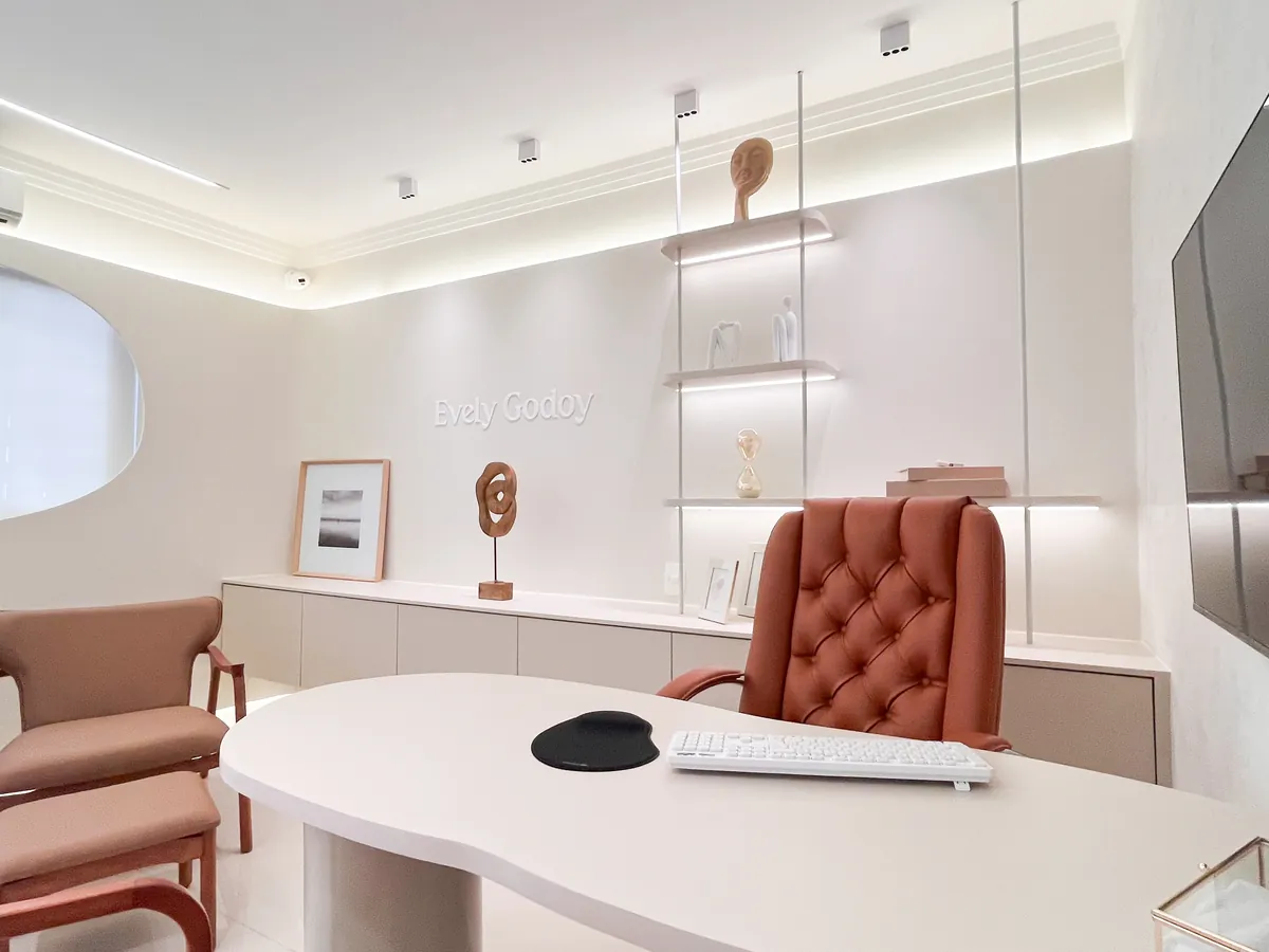Consultório adulto com mesa de atendimento, cadeira de couro, poltronas e janela oval